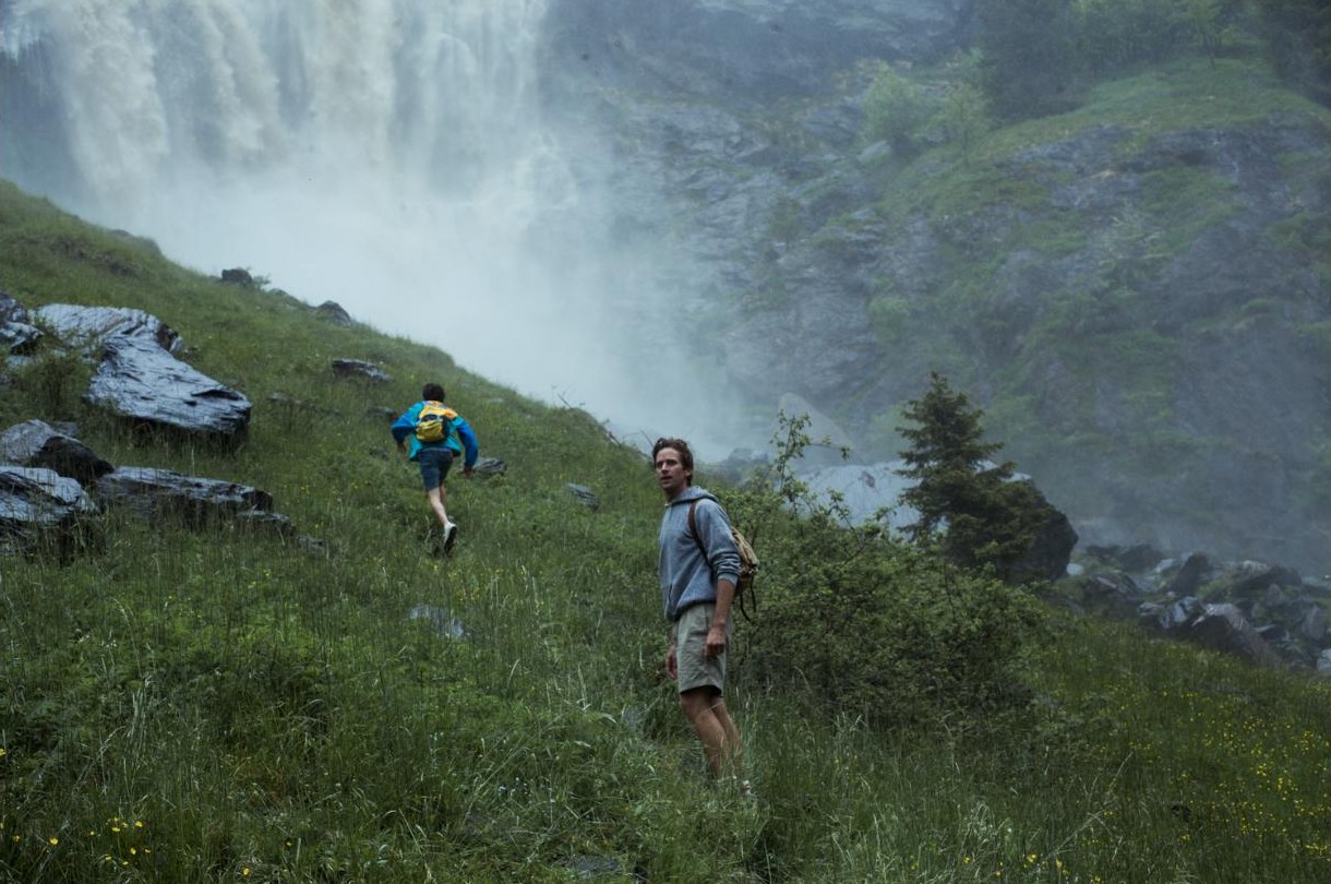 Elio and Oliver climb a hillside below a waterfall in northern Italy