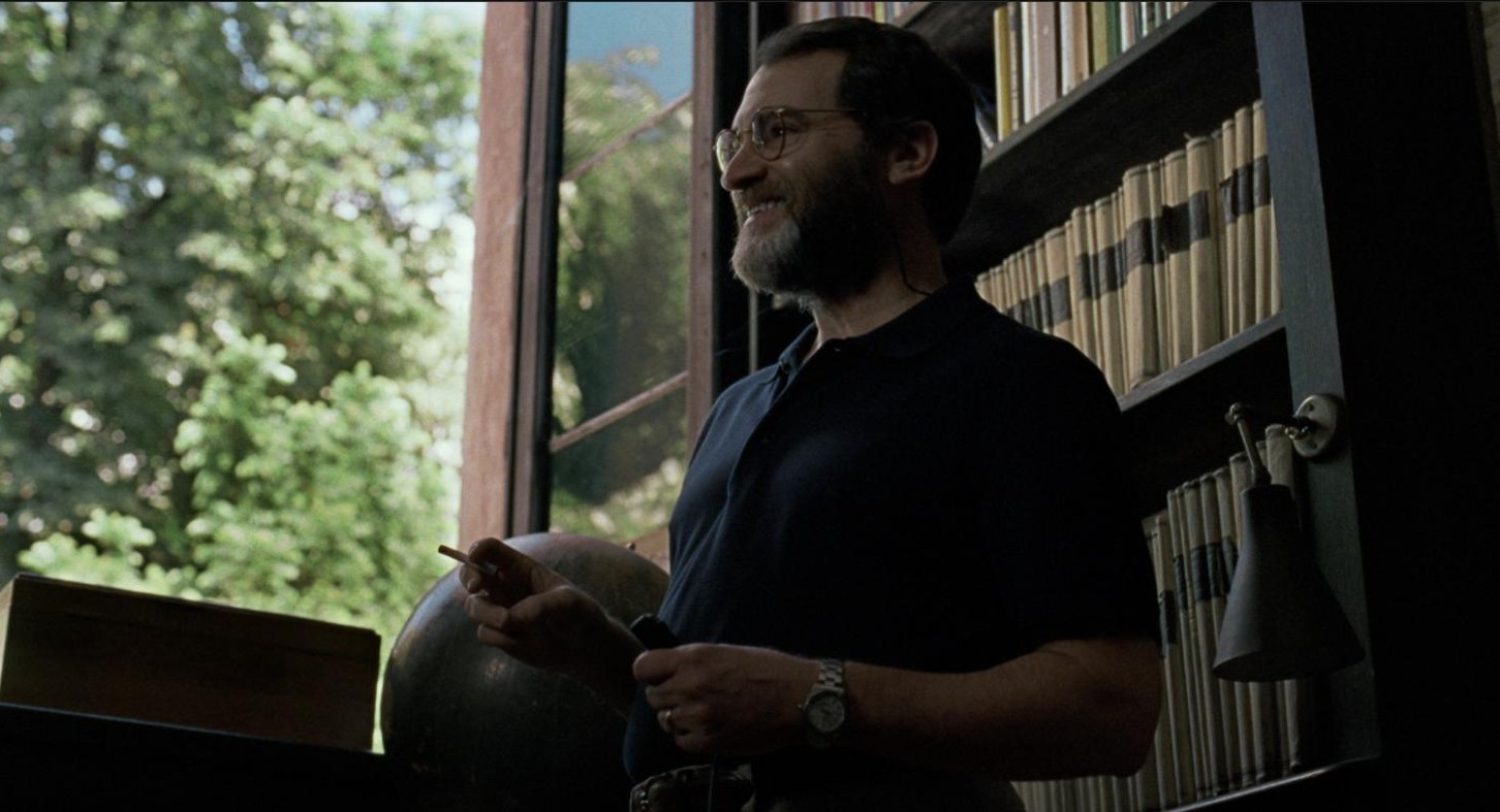Mr. Perlman smiles in his study, bookshelves behind him