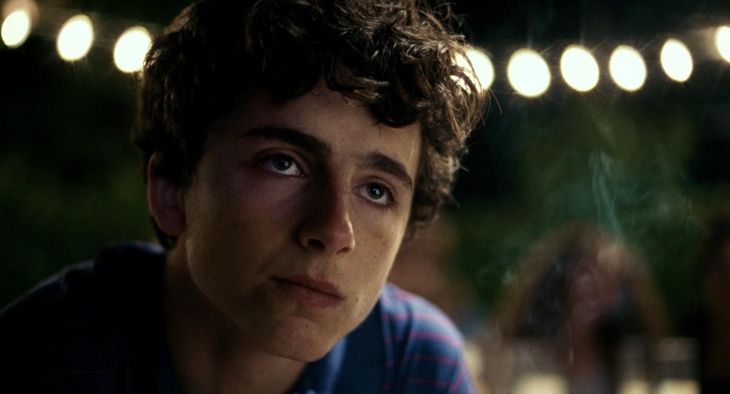 Close-up of Elio's face at night under strings of party lights